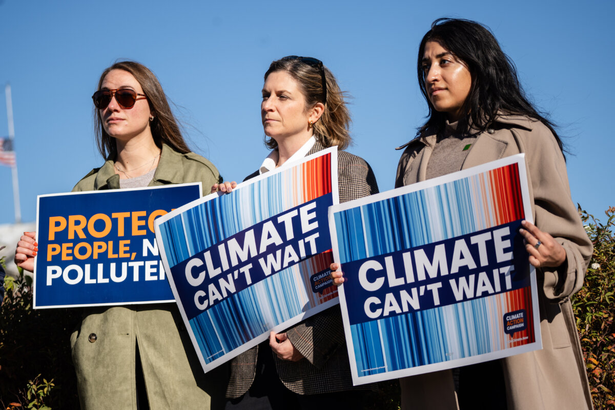Climate activists hold signs during a press conference with members of the House of Reps. Sustainable Energy & Environment Coalition (SEEC) on Capitol Hill in Washington on Nov. 13, 2025. (Madalina Kilroy/The Epoch Times)