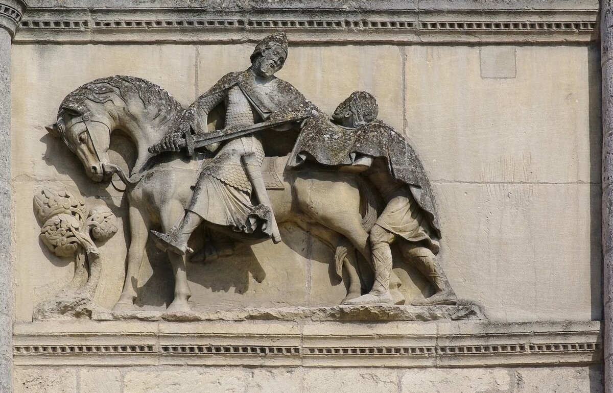 A statue of Saint Martin of Tours cutting his cloak in two to share with a beggar. Façade of the Cathedral of Saint-Pierre (XII century), Angoulême, Charente, France. A few warm days are associated with this act of kindness. (Public Domain)