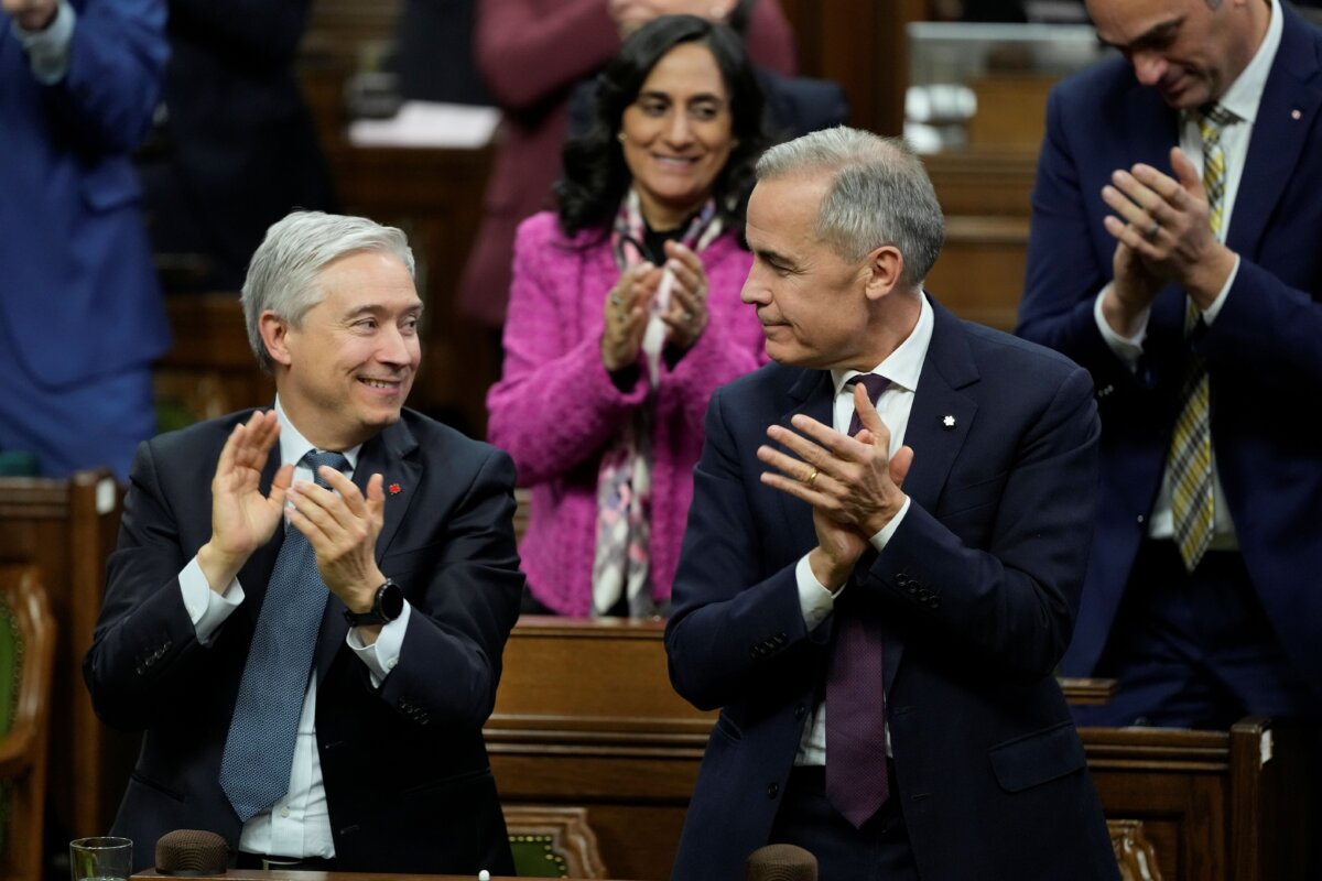 Prime Minister Mark Carney and Finance Minister Francois-Philippe Champagne applaud following a vote on the federal budget on Parliament Hill in Ottawa, on Nov. 17, 2025. (The Canadian Press/Adrian Wyld)