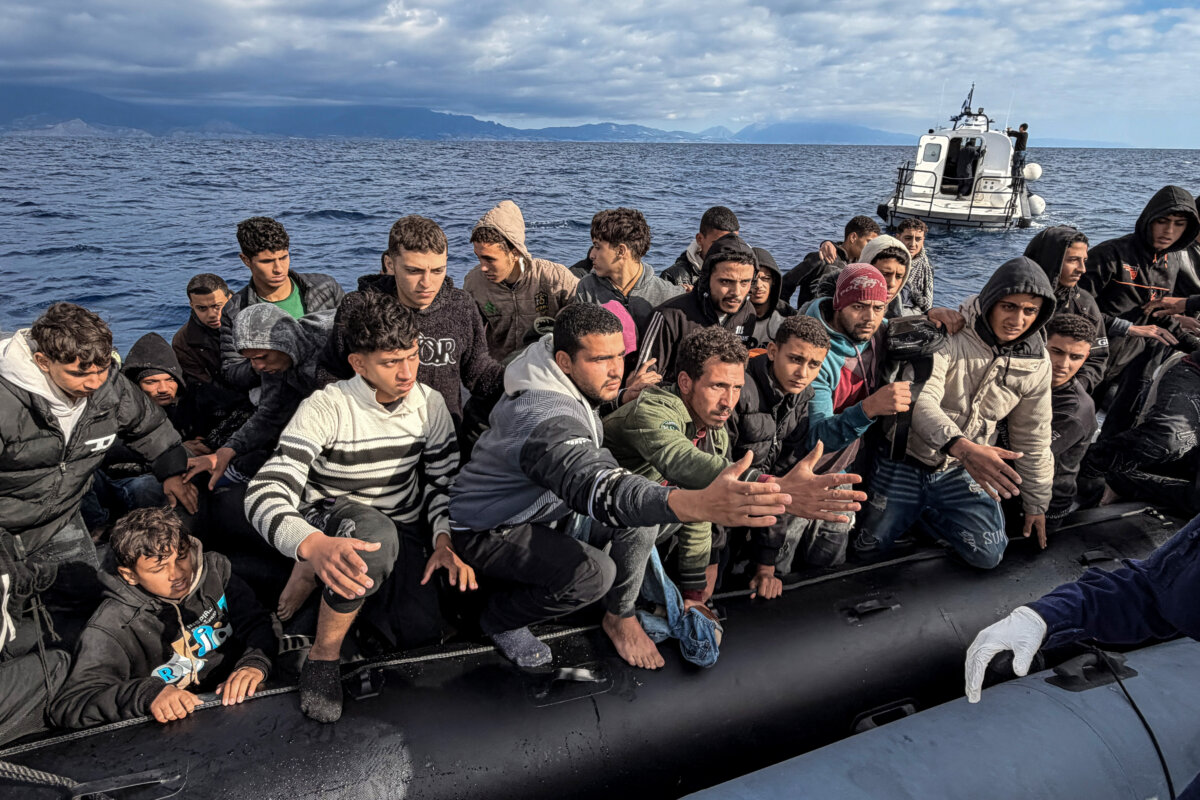 TOPSHOT - Migrants, attempting to cross the Mediterranean sea react while sitting on a dinghy after being picked up at sea, as they are rescued by the Greek Coast Guard, off the south coast of Crete island, on November 18, 2025. (Photo by Eleftherios Elis MITZA / AFP) (Photo by ELEFTHERIOS ELIS MITZA/AFP via Getty Images)