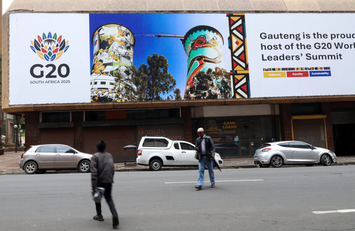 People walk in front of a Group of 20 banner as South Africa prepares to host the Group of 20 Summit from Nov. 22 to Nov. 23, in Johannesburg on Nov. 18, 2025. (Siphiwe Sibeko /Reuters)