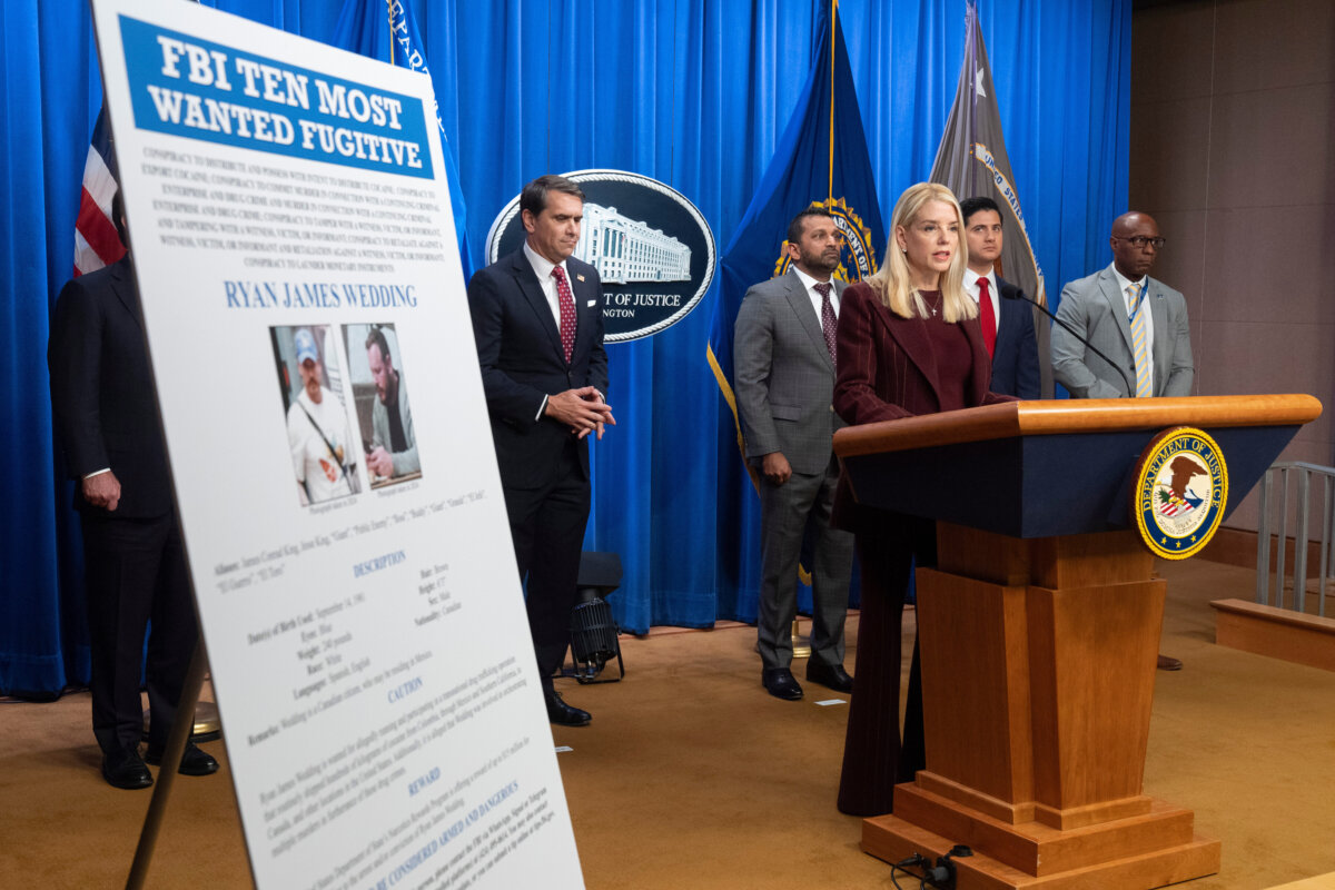 Attorney General Pam Bondi stands near wanted poster for Canadian fugitive Ryan James Wedding as she speaks with reporters during a news conference at the Department of Justice, on Nov. 19, 2025, in Washington. (AP Photo/Mark Schiefelbein)