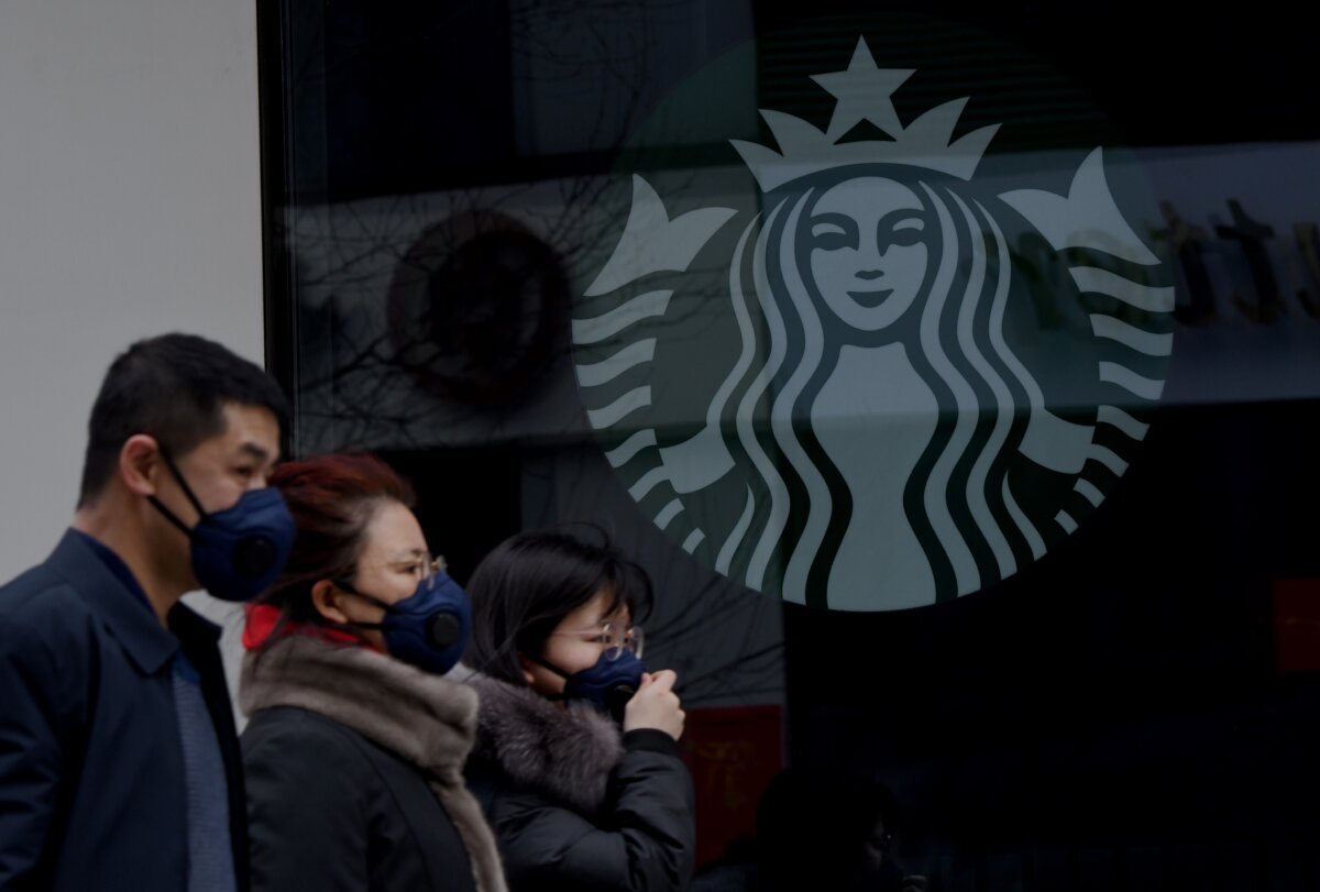 People wearing protective face masks walk past a closed Starbucks coffee shop at a grocery in Beijing on Jan. 29, 2020. (Noel Celis/AFP via Getty Images)