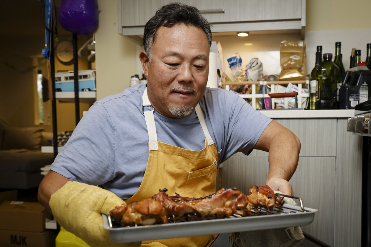 Taichi Kitamura pulls his recipe of Thanksgiving teriyaki turkey from the oven at his home in Seattle, Washington, on Oct. 24, 2025. (Kevin Clark/The Seattle Times/TNS)