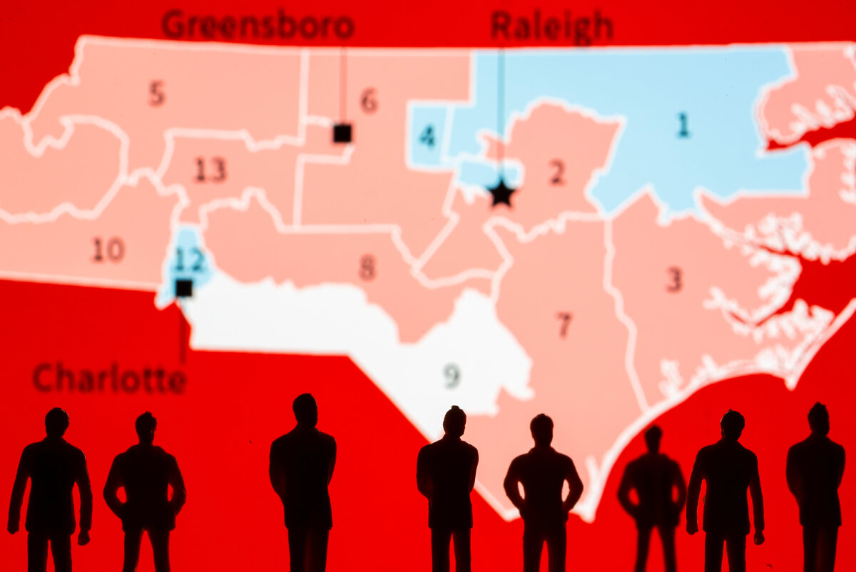Small toy people figures in front of displayed North Carolina district maps in this illustration taken on Aug. 13, 2021. (Dado Ruvic/Illustration/Reuters)