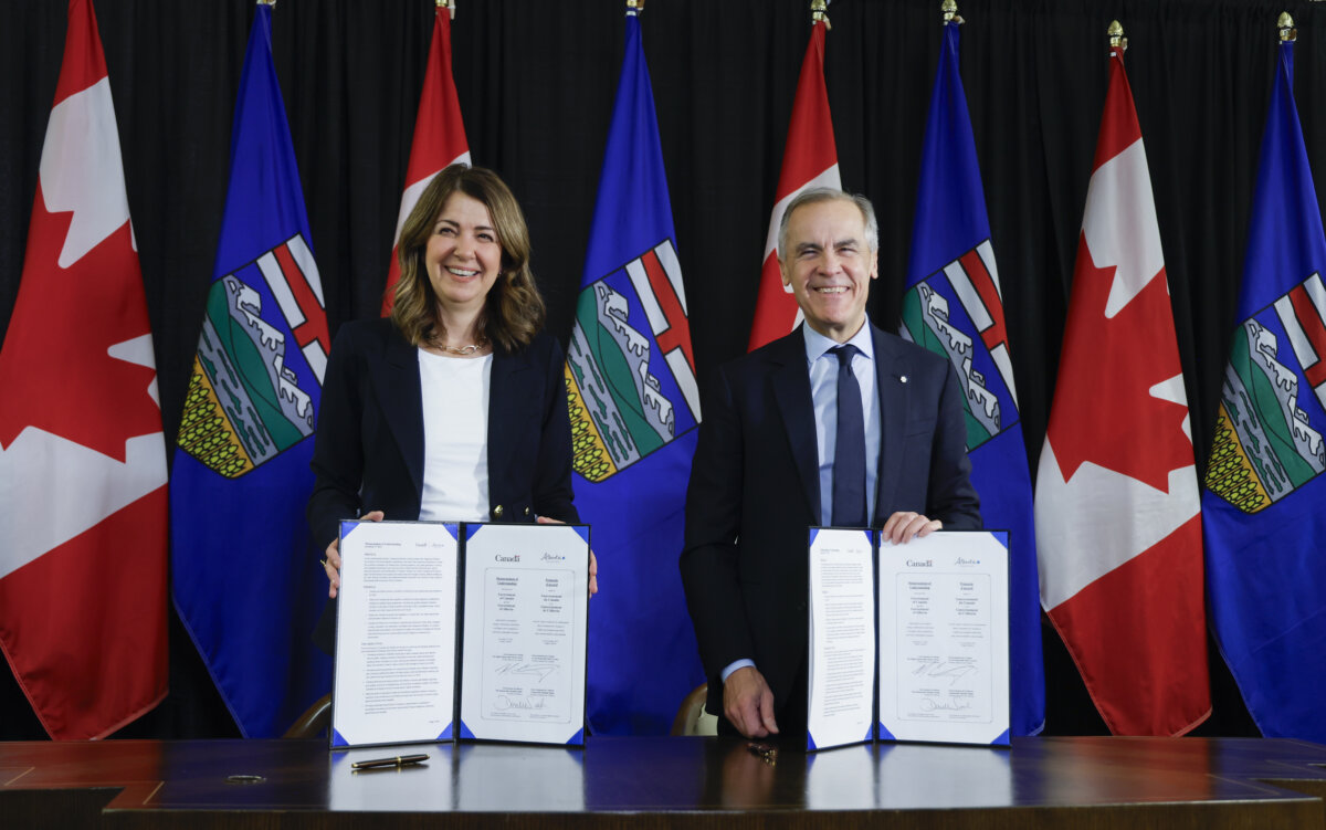Prime Minister Mark Carney signs an MOU with Alberta Premier Danielle Smith in Calgary on Nov. 27, 2025. (Jeff McIntosh/The Canadian Press)