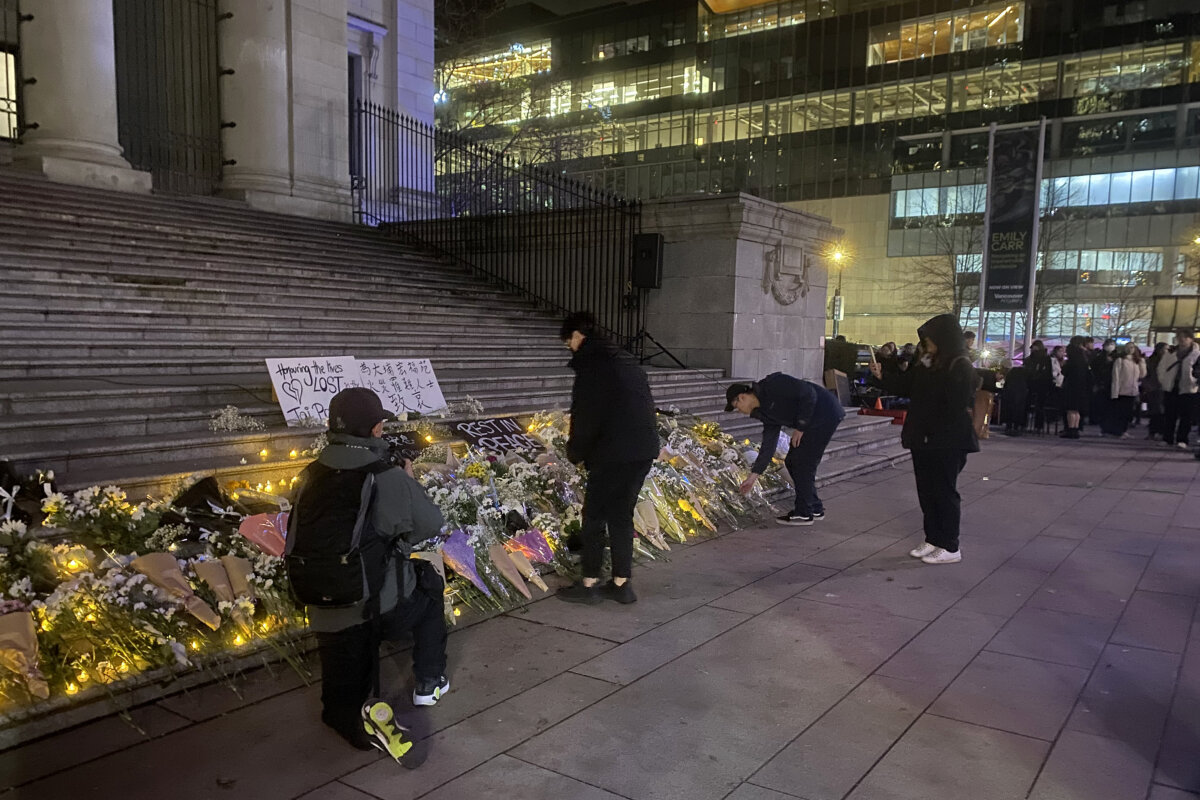 Mourners lay flowers at a makeshift memorial in front of the Vancouver Art Gallery to pay tribute to victims who lost their lives in the deadly Hong Kong fire, in Vancouver, on Nov. 30, 2025. (The Canadian Press/Nono Shen)