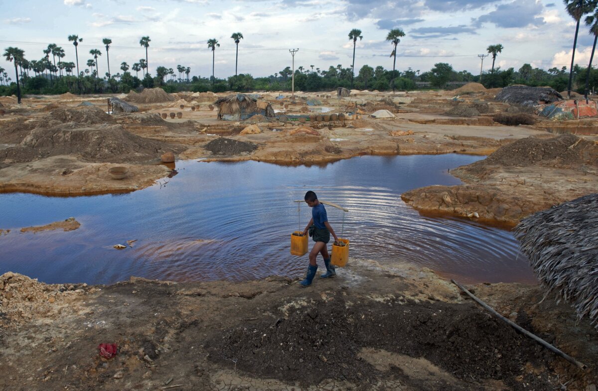 A worker carrying containers next to pools in a mining waste dump area in Monywa, northwestern Myanmar, on Aug. 28, 2013. (Ye Aung Thu /AFP via Getty Images)
