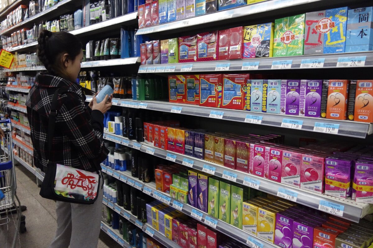 A woman browses items for sale beside a shelf of condoms (R) at a supermarket in Beijing on April 24, 2013. (Wang Zhao /AFP via Getty Images)