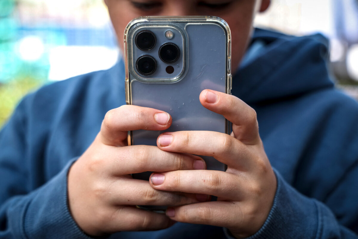 A 14-year-old boy posing at his home near Gosford as he looks at social media on his mobile phone in New South Wales, Australia, on Oct. 24, 2025. (David Gray/AFP via Getty Images)