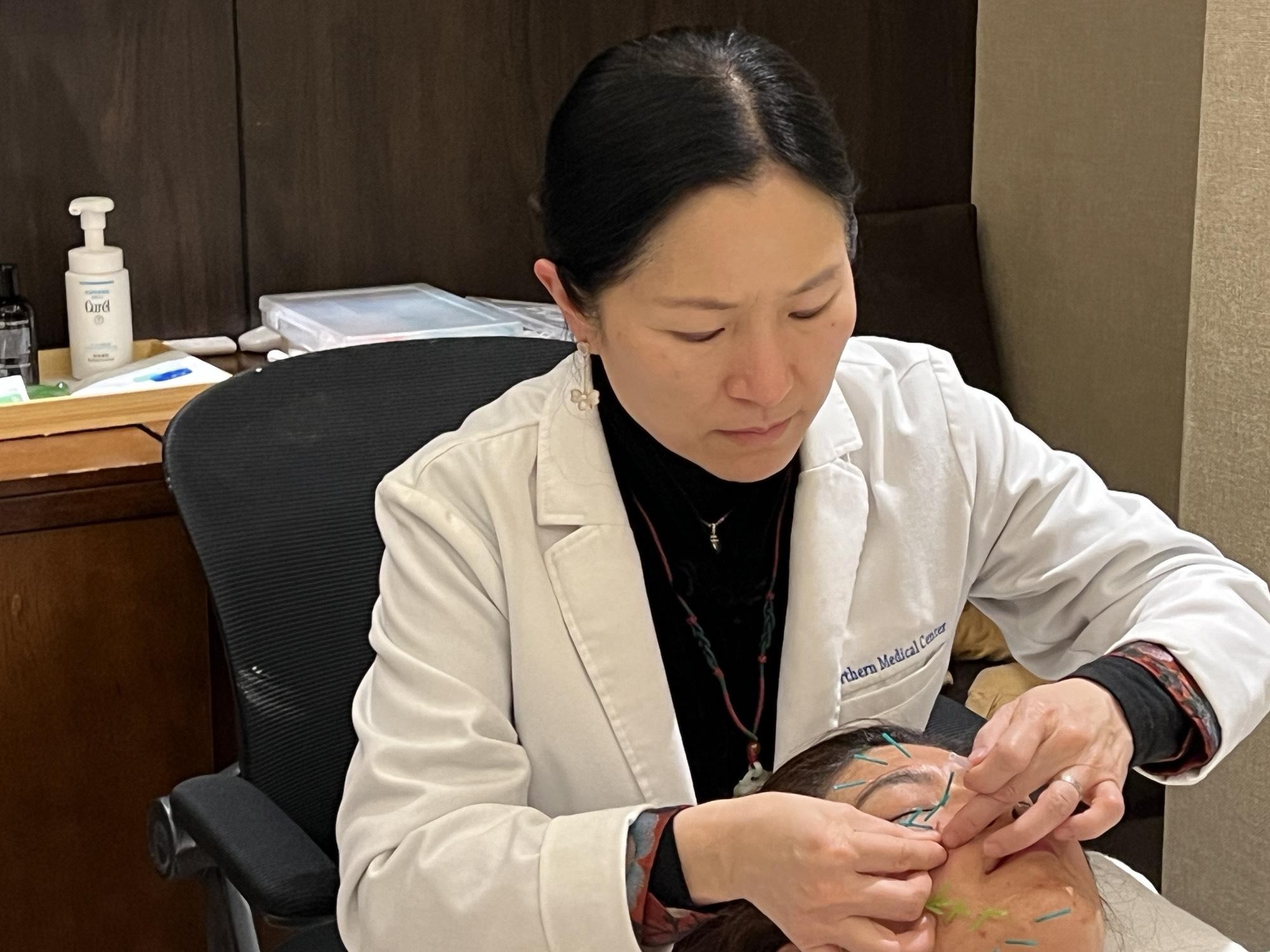 Serene Feng performing facial acupuncture on a patient. (趙芬妮/The Epoch Times)