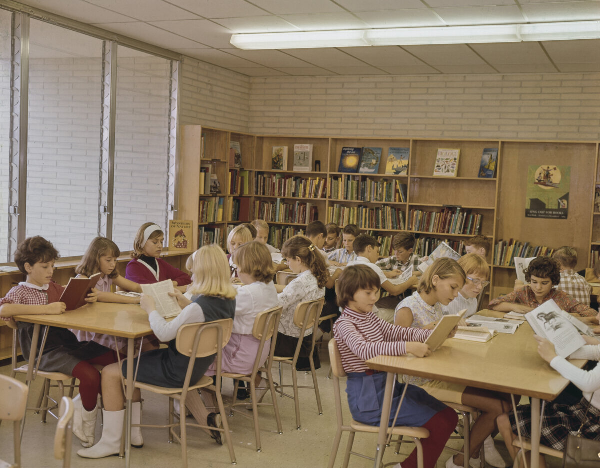 Elementary students sit around tables reading books in the library of an elementary school in the U.S., circa 1975. (FPG/Archive Photos/Getty Images)