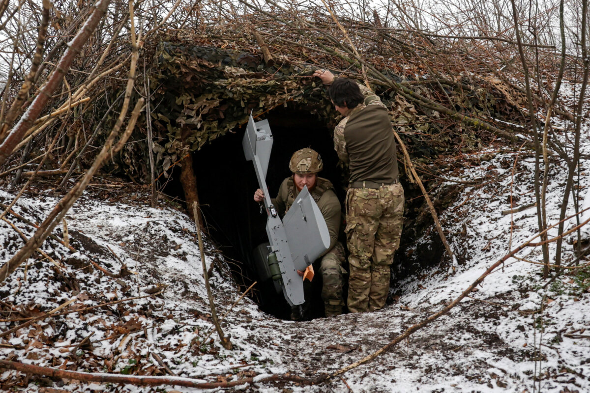 Ukrainian servicemen leave their dugout with a Darts middle range drone before launching it towards Russian troops from their position, in Donetsk region, Ukraine, on Dec. 16, 2025. (Sofiia Gatilova/Reuters)