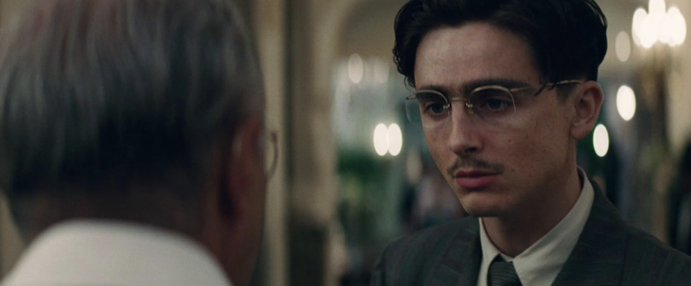 older man talking to young man with glasses in Marty Supreme