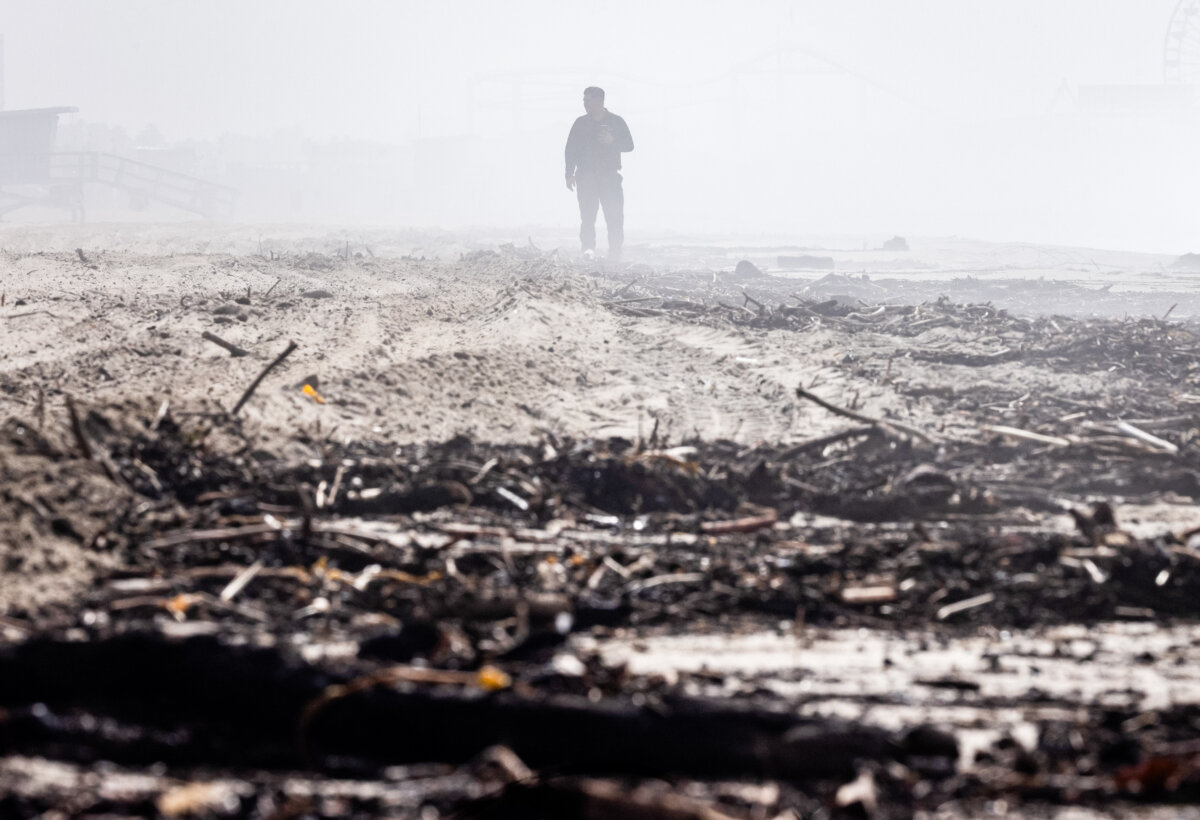 A man walks over debris left from the Palisades Fire and heavy rains in Santa Monica, Calif., on Feb. 27, 2025. (John Fredricks/The Epoch Times)