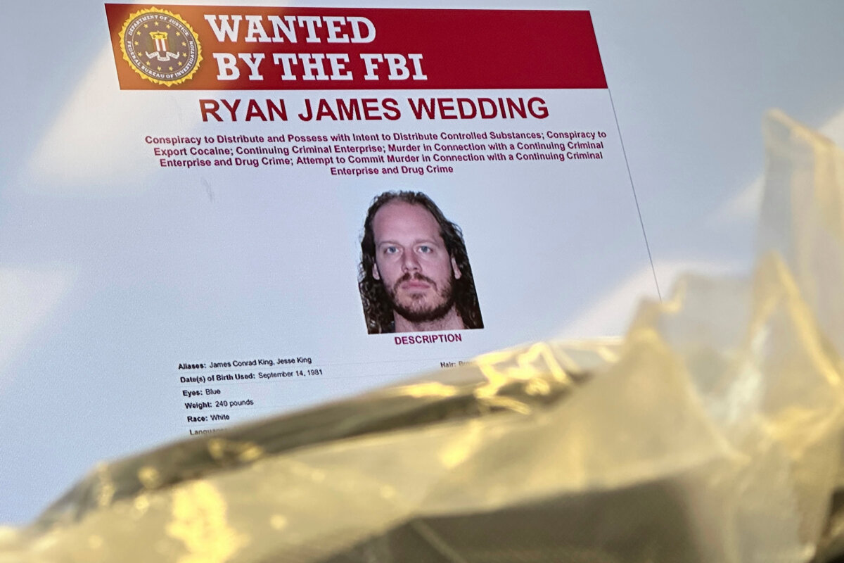 FILE - An image of former Canadian Olympic snowboarder Ryan Wedding, who is a fugitive and been charged with allegedly running and participating in a transnational drug trafficking operation, is displayed on a video monitor along with bricks of cocaine, foreground, during a news conference at the FBI offices in Los Angeles, on Oct. 17, 2024. (AP Photo/Damian Dovarganes, File)