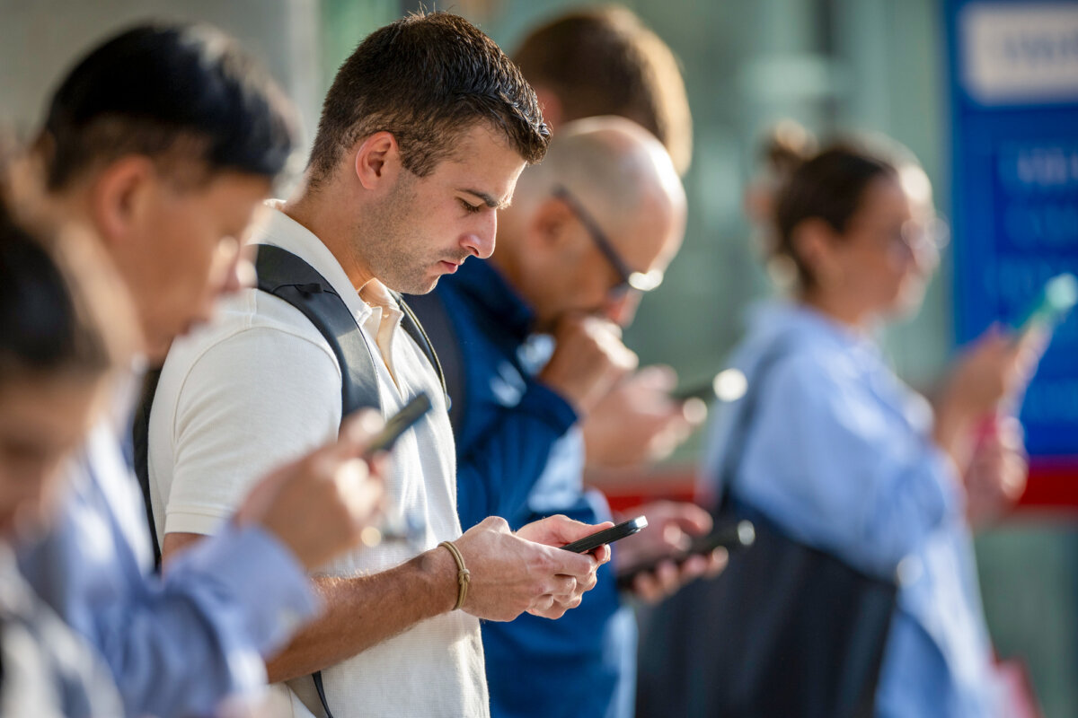 People check their phones while waiting for the train to arrive in Stamford, Conn., on Aug. 28, 2023. (John Moore/Getty Images)