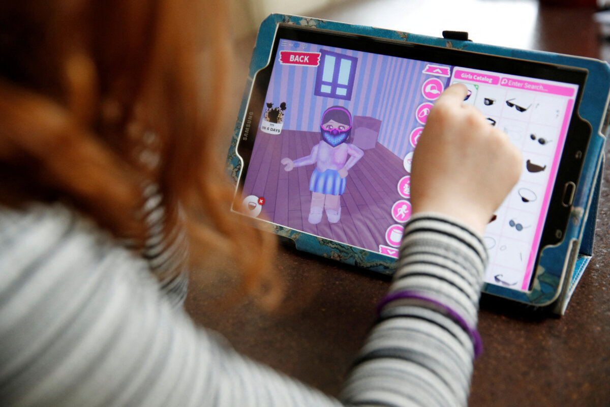 A child adds a face mask to her character on the Roblox game platform at her home in Manchester, England, on April 5, 2020. (Phil Noble/Reuters)