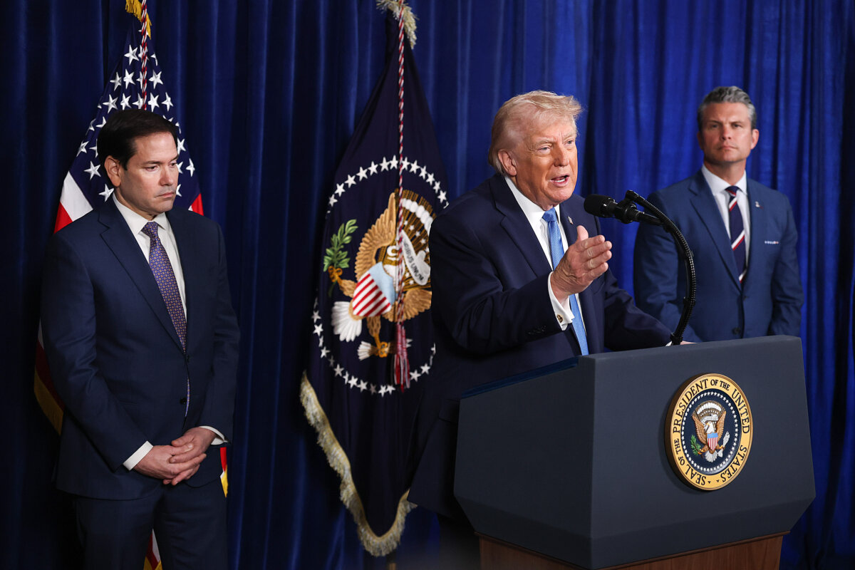 Secretary of State Marco Rubio and Secretary of War Pete Hegseth listen as President Donald Trump addresses the media during a press conference at his Mar-a-Lago club in Palm Beach, Fla., on Jan. 3, 2026. (Joe Raedle/Getty Images)