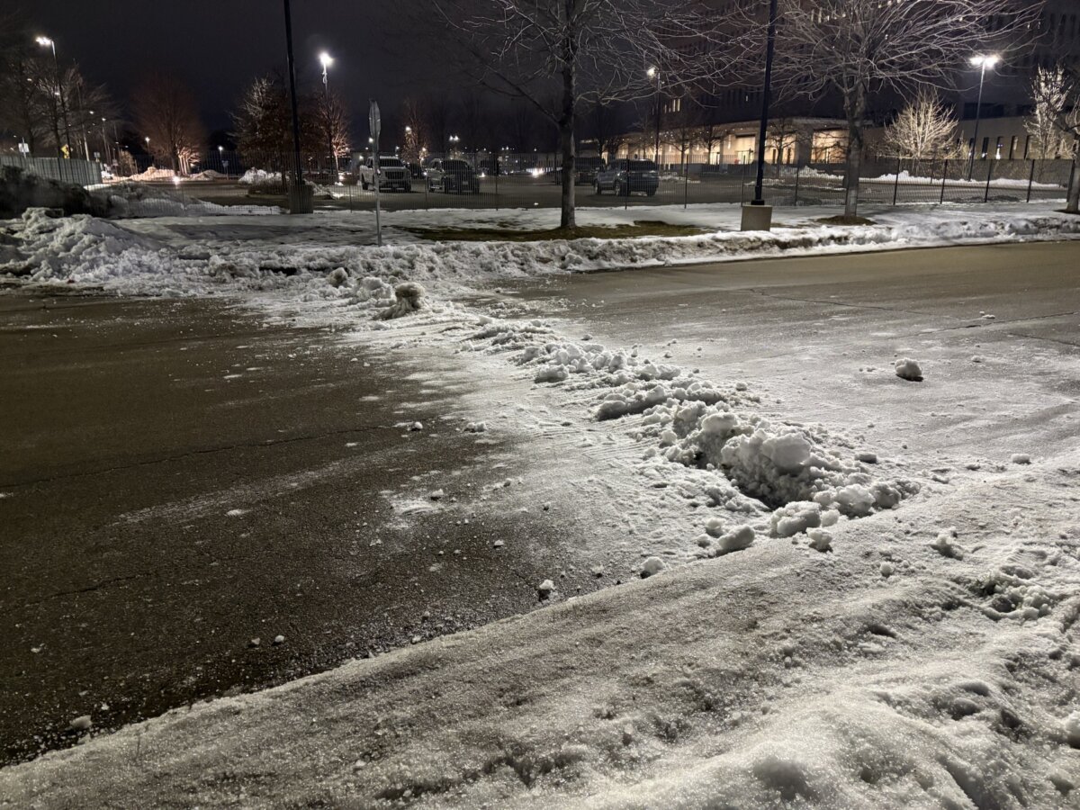 An anti-ICE protester attempted to pile snow on the road near the Bishop Henry Whipple Federal Building on Jan. 9 as an attempt to make it harder for law enforcement to exit the area. (Nathan Worchester / The Epoch Times 0