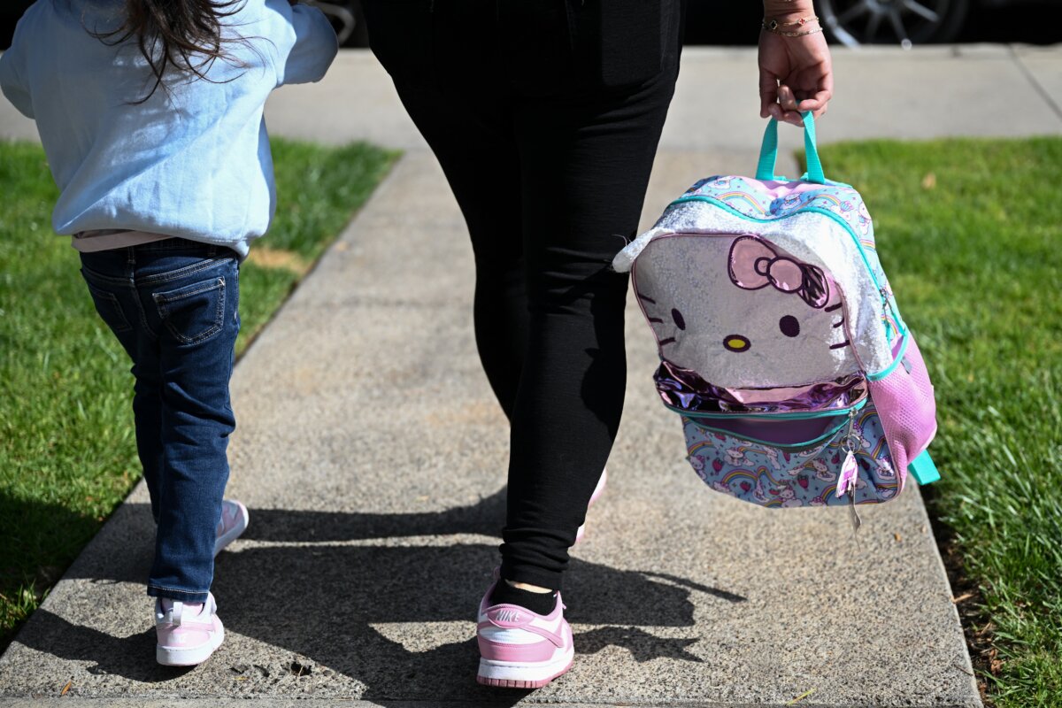 An illegal immigrant mother from Mexico holds hands with her young daughter, who is a U.S. citizen, on their way to daycare from their home in San Diego on April 24, 2025. (Photo by Patrick T. Fallon / AFP via Getty Images)