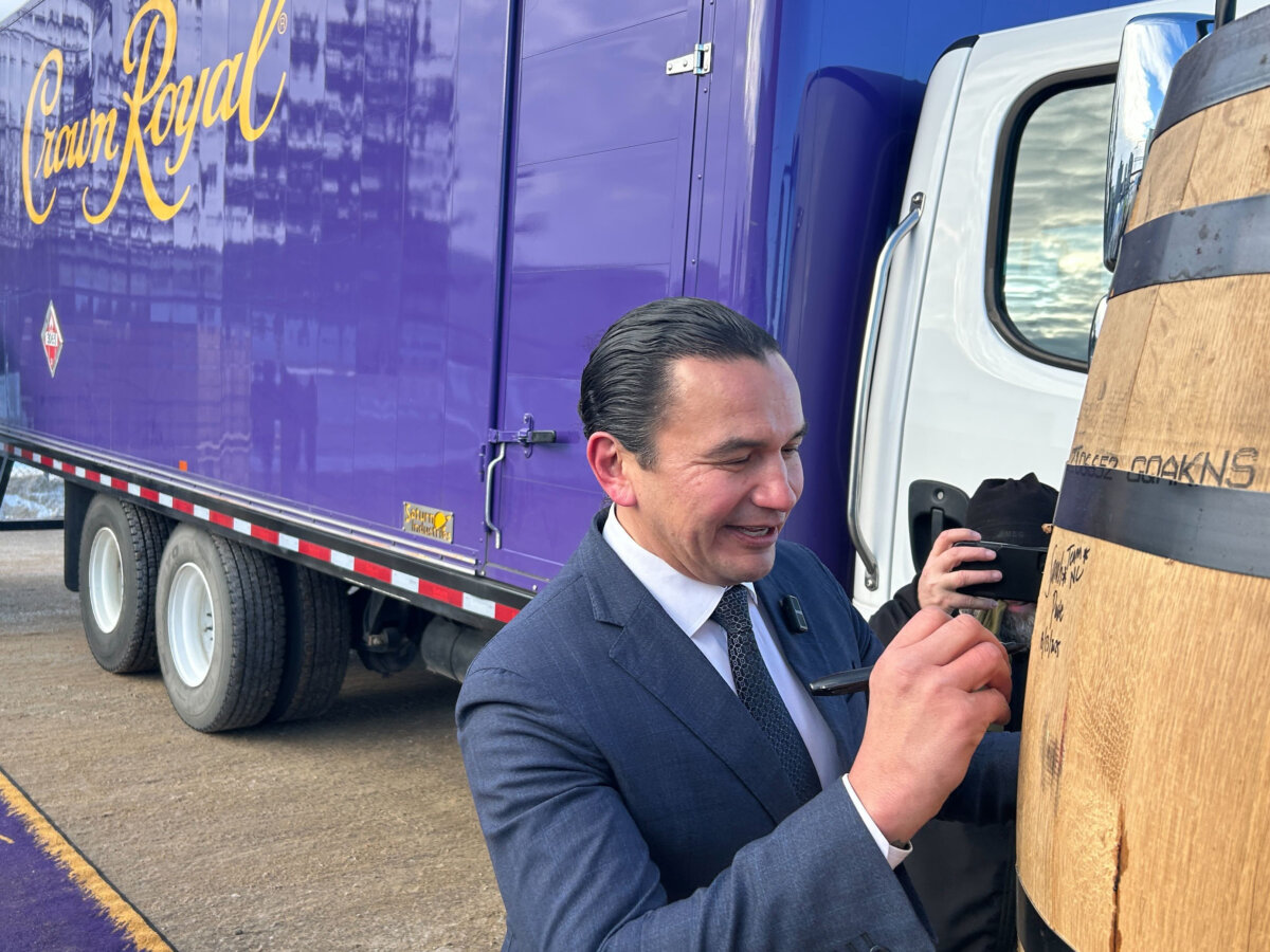 Manitoba Premier Wab Kinew signs barrels outside the Diageo plant where Crown Royal whisky is produced, in Gimli, Man., on Jan. 13, 2026. Kinew is calling on Ontario Premier Doug Ford to cancel a planned boycott of the whisky. (The Canadian Press/Steve Lambert)