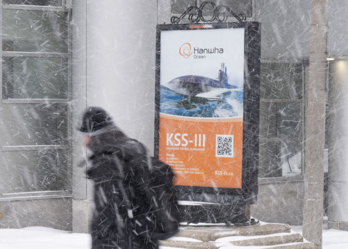 A man walks past an ad for military submarines in the downtown core near Parliament Hill in Ottawa on Jan. 15, 2026. (The Canadian Press/Adrian Wyld)