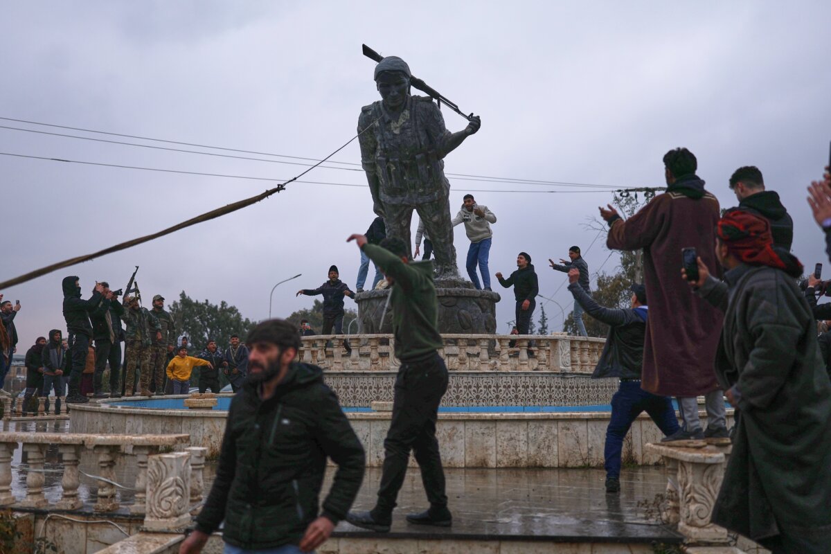 Residents topple a statue of a female Kurdish fighter after the takeover of the town by Syrian government forces from US-backed Syrian Democratic Forces in Tabqa, eastern Syria, on Jan. 18, 2026. (Ghaith Alsayed/AP Photo)