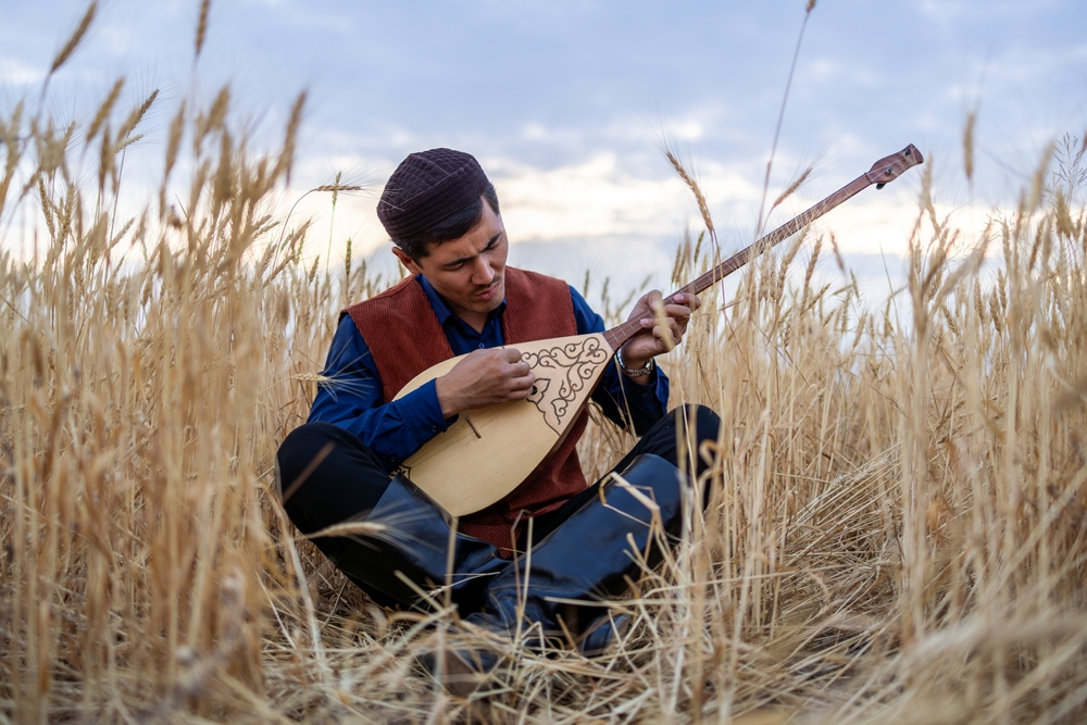 A Kazakh man in the steppe of Kazakhstan, playing and singing with a dombra in his hands. (Alex Buzurnyuk/Shutterstock)
