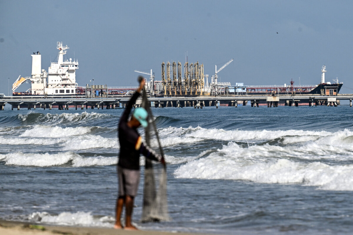 A fisherman stands by the sea as a tanker is docked at the El Palito refinery pier, in Puerto Cabello, Carabobo state, Venezuela, on Jan. 22, 2026. (Ronaldo Schemidt/AFP via Getty Images)