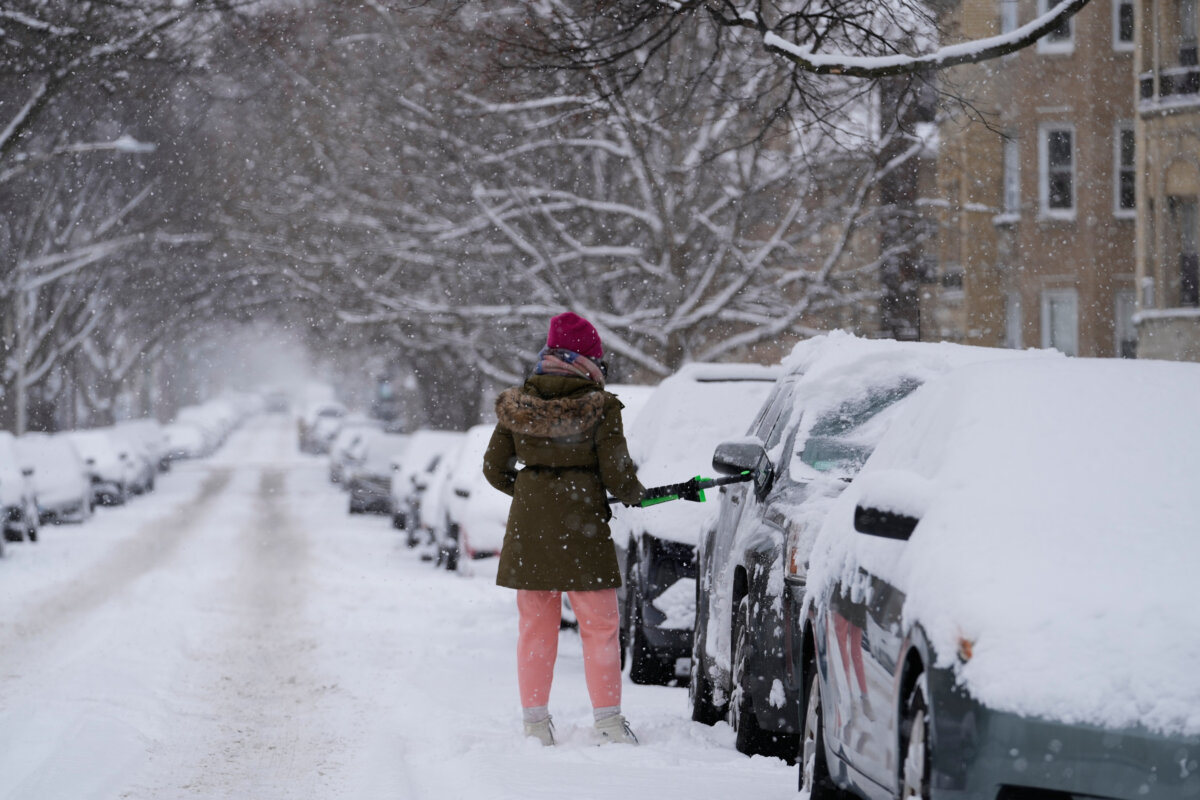A person cleans the snow from a car during a snowy day in Chicago, on Jan. 25, 2026. (Nam Y. Huh/AP Photo)