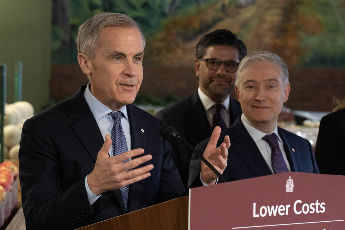 Finance and National Revenue Minister Francois-Philippe Champagne looks on as Prime Minister Mark Carney speaks during an announcement at a grocery store in Ottawa on Jan. 26, 2026. (The Canadian Press/Adrian Wyld)