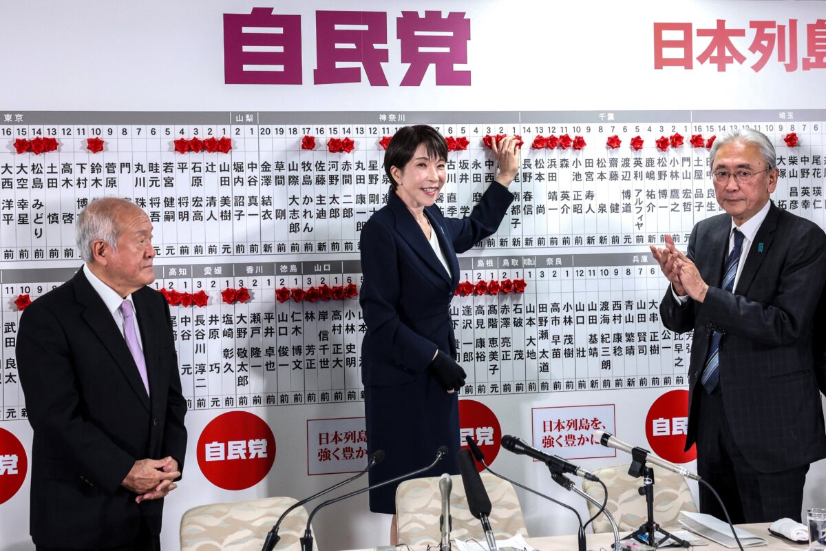 Japanese Prime Minister and President of the Liberal Democratic Party (LDP) Sanae Takaichi (C), standing next to LDP Secretary-General Shunichi Suzuki (L) and LDP Election Strategy Chief Keiji Furuya, places a red paper rose on the name of an elected candidate at the LDP headquarters during the House of Representatives election in Tokyo on Feb. 8, 2026. (Kim Kyung-Hoon/Pool/AFP/Getty Images)