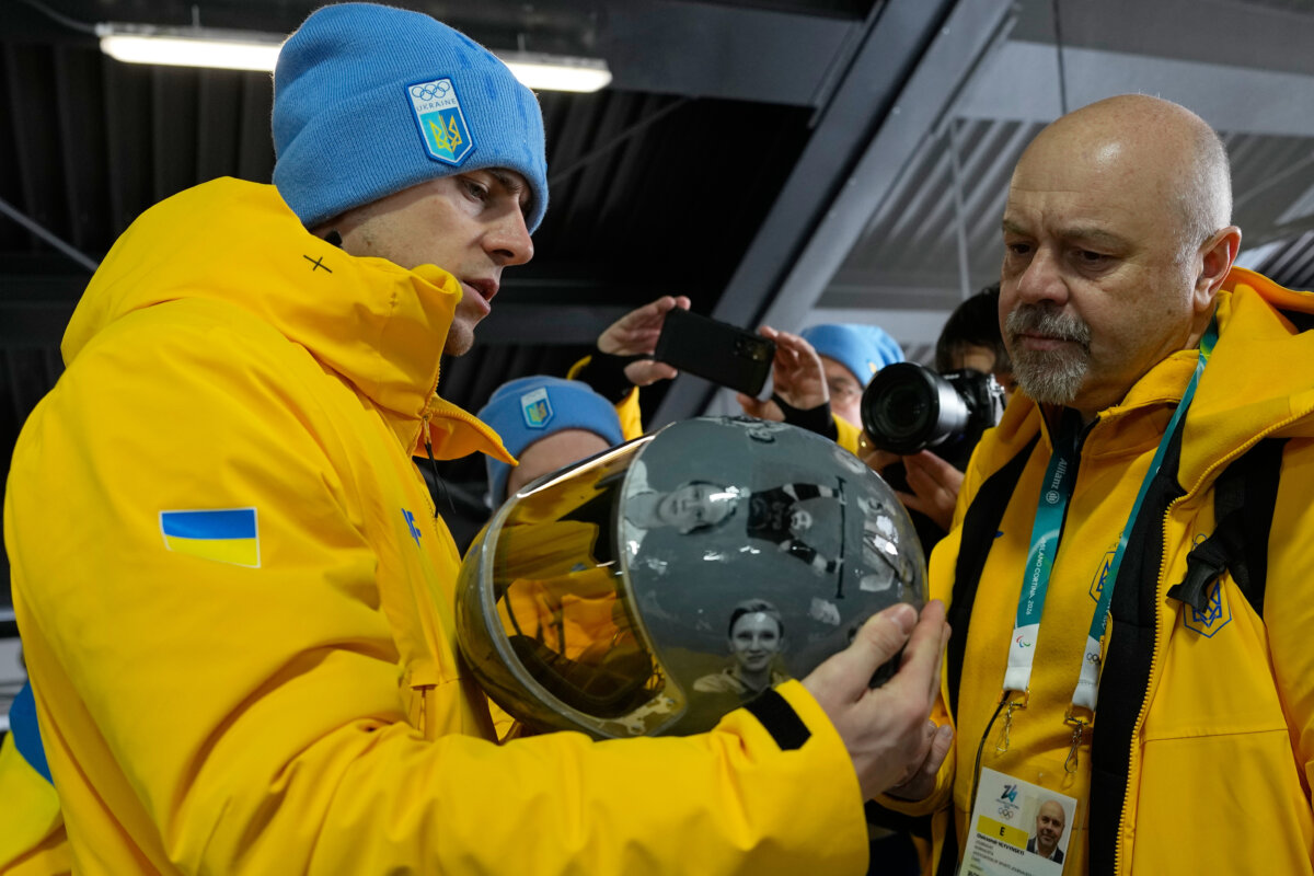Ukrainian skeleton athlete Vladyslav Heraskevych left, holds his crash helmet at the mixed zone of the sliding center at the 2026 Winter Olympics, in Cortina d'Ampezzo, Italy, on Feb. 12, 2026. (Alessandra Tarantino/AP Photo)