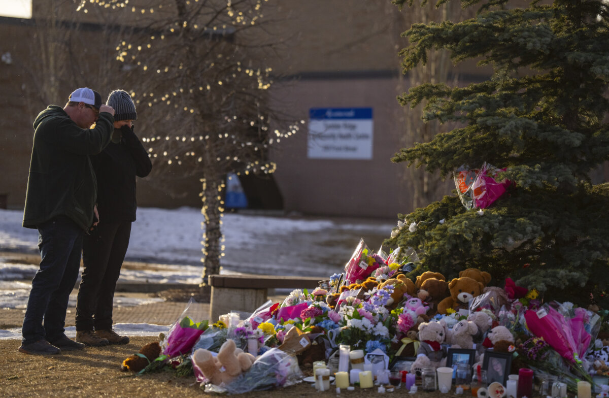 People pay their respects by a memorial for the victims of a mass shooting in Tumbler Ridge, B.C., on Feb. 12, 2026. (The Canadian Press/Christinne Muschi)