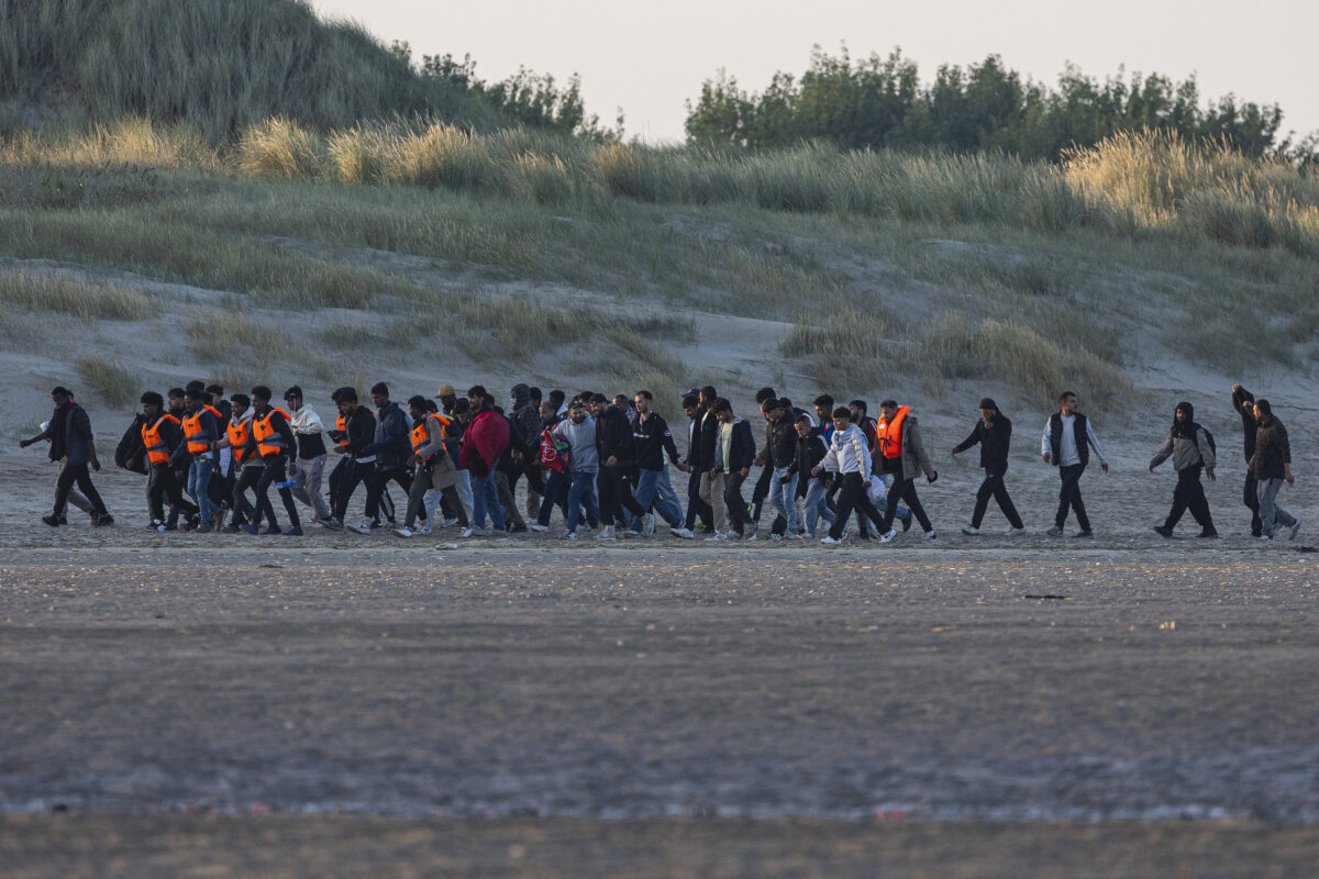 Migrants walk on the beach to wait for a smuggler's boat to attempt to cross the English Channel, in Gravelines, northern France, on Aug. 11, 2025. (Sameer Al-Doumy/AFP via Getty Images)