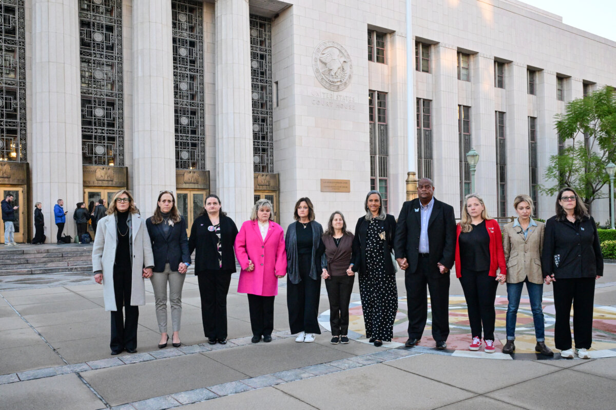 Parents and family members, including some plaintiffs in the case, hold hands as they pose together before entering Los Angeles Superior Court for the social media trial tasked to determine whether social media giants deliberately designed their platforms to be addictive to children, in Los Angeles, on Feb. 18, 2026. (Frederic J. Brown/AFP via Getty Images)