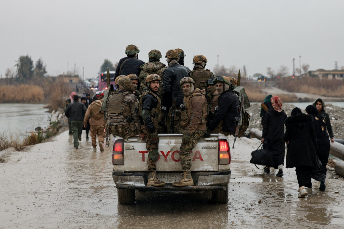 Military personnel in a vehicle at the crossing connecting the two banks of the Euphrates River, as they attempt to cross to the other side after the Syrian Democratic Forces (SDF) withdrew from Deir al-Zor province and the Syrian army took full control over the area, in Deir al-Zor, Syria, on Jan. 18, 2026. (Khalil Ashawi/Reuters)
