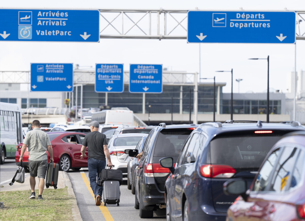 Travellers walk through traffic with their luggage as they try to catch their flights at Montréal Trudeau International Airport, in Montreal, on Sept. 7, 2023. (The Canadian Press/Christinne Muschi)