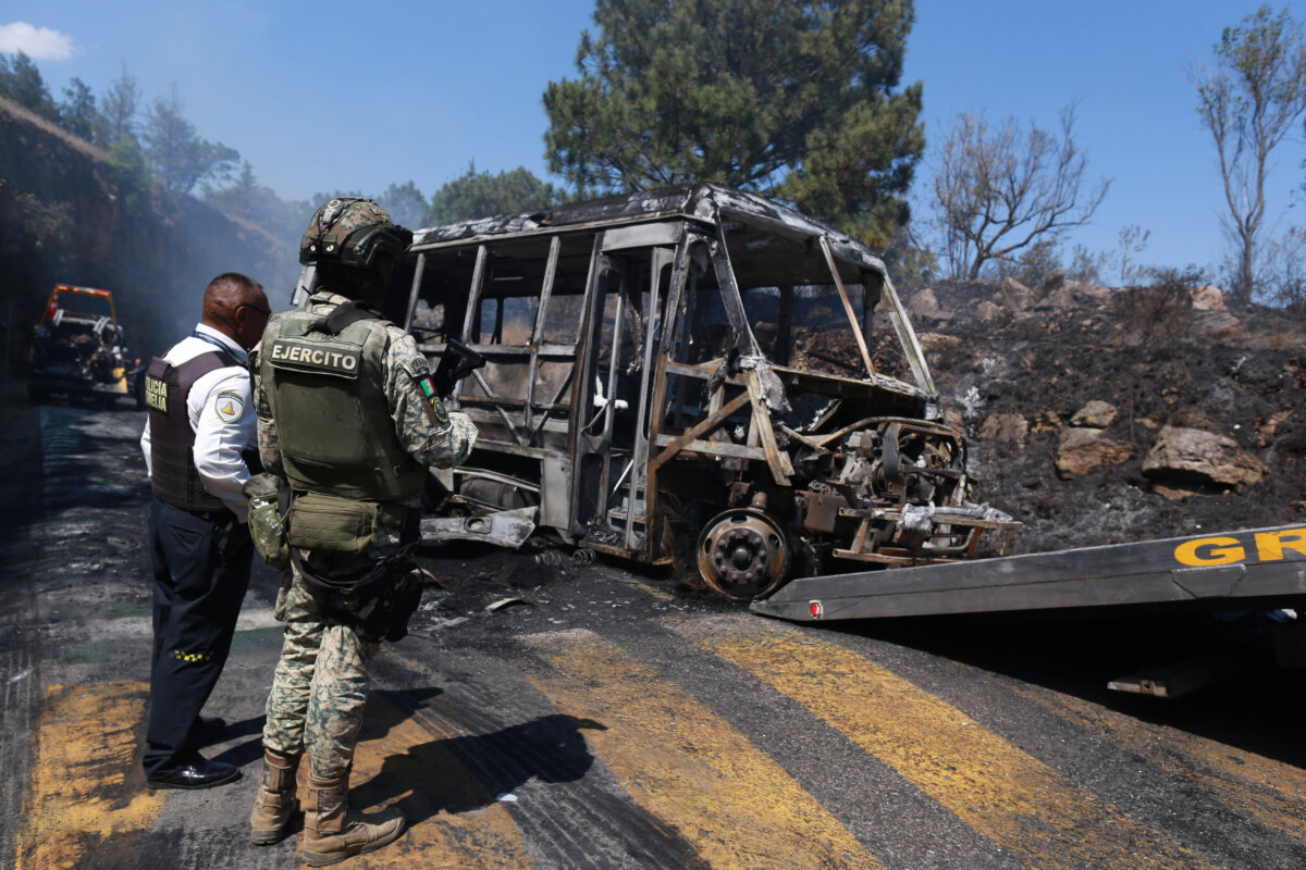A soldier stands guard by a charred vehicle that was set on fire in Cointzio, Mexico, on Feb. 22, 2026, after the Mexican Army killed cartel leader Nemesio Oseguera, known as "El Mencho.” (AP Photo/Armando Solis)