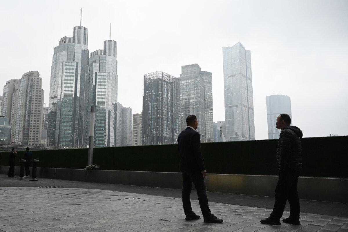 Two men chat outside office buildings in the central business district in Beijing on March 4, 2026. (Greg Baker/AFP via Getty Images)