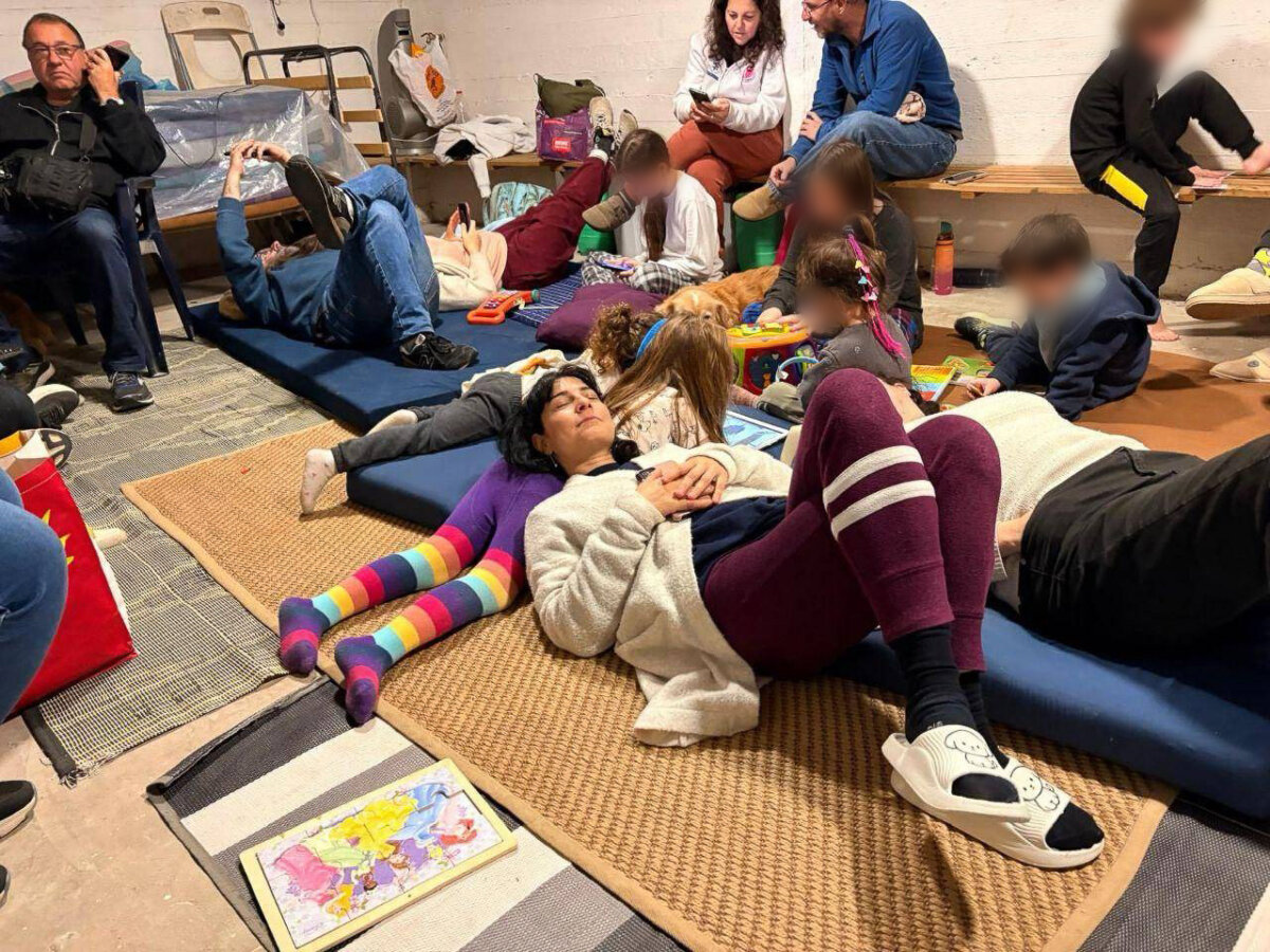 Racheli alongside children and adults in an Israeli bomb shelter on the night of March 10 to March 11. (This image was digitally altered to conceal children's identities.) (Vadim Berestetsky)