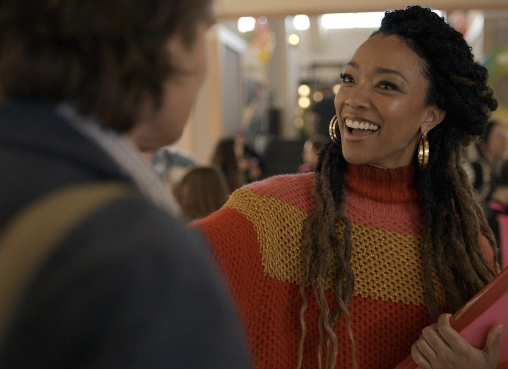 woman in red sweater greets man in She Dances