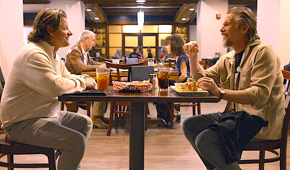 two men sit at a table in She Dances