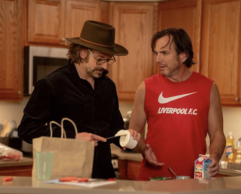 man in black shirt and hat and man in red shirt in kitchen in Is This Thing On?