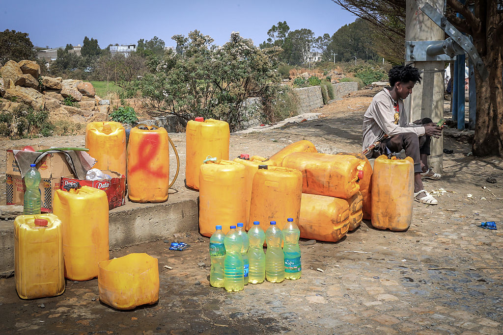 A man counts money while waiting for customers at an informal roadside shop selling fuel in bottles and bidons amid fuel shortages in Mekelle, Ethiopia, on March 4, 2026. (Abel Gerezgiher/AFP via Getty Images)