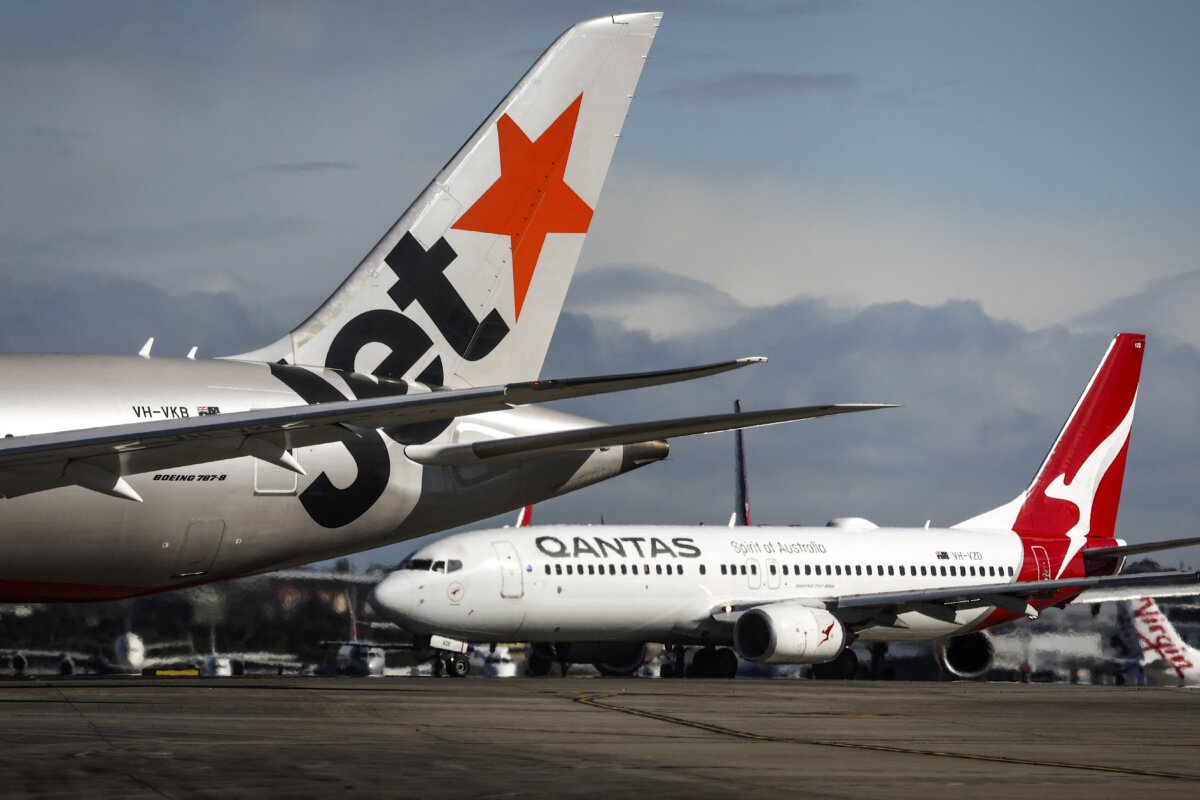 A Jetstar Airlines Boeing 787-8 plane and a Qantas Airways Boeing 737-800 plane line up with other aircraft on the runway at Sydney International Airport on a windy day in Sydney on June 25, 2025. According to local media, Airservices Australia has ordered Sydney Airport to shut two of its three runways, leading to a number of flight delays and cancellations due to high winds. (Photo by DAVID GRAY / AFP) (Photo by DAVID GRAY/AFP via Getty Images)