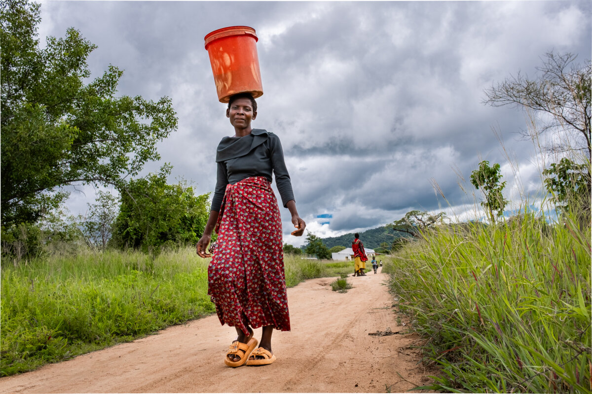 A woman carries a bucket on her head outside of Mangochi, Malawi, on Feb. 18, 2026. (John Fredricks/The Epoch Times)