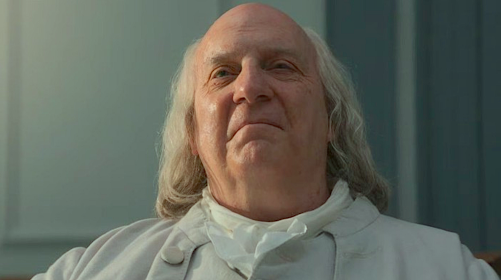 man with long grey hair and white jacket in A Great Awakening
