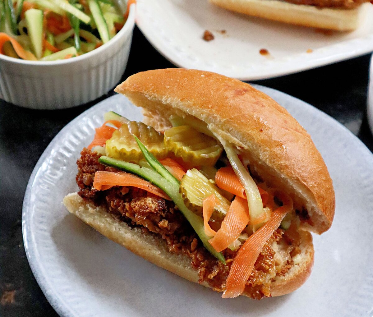 An air-fried chicken sandwich glazed with a glossy sauce made from honey, dark soy, and garlic, and topped with cucumber salad. (Gretchen McKay/Pittsburgh Post-Gazette/TNS)